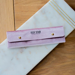 A pink velvet jewelry organiser pouch with gold snap buttons and 'ISSY STAR' printed on the front.