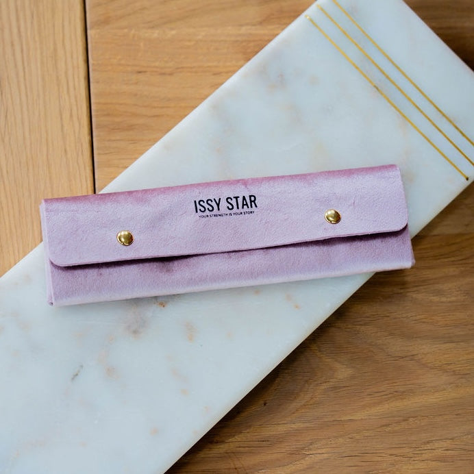 A pink velvet jewelry organiser pouch with gold snap buttons and 'ISSY STAR' printed on the front.